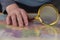 A man holds a magnifying glass in his hand over a map. A middle-aged man with a magnifying glass in a gold frame. The names are