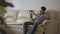 Man holds mobile phone on gimbal sitting on the sofa at home. Smartphone Gimbal the guy shoots himself.