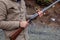 A man holds an old, antique, double-barrel shotgun to his waist, pointing the barrel downrange, ready to load