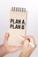 A man holds a pen and a bolknot in his hands with the inscription - Plan A, Plan B