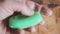 A man holds a piece of green soap in a wet palm. Lathers hand. Bathhouse