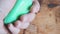 A man holds a piece of green soap in a wet palm. Lathers hand. Bathhouse. Preparation for washing. Background wood texture.