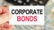 A man holds a piece of paper with the text: corporate bonds. Business and finance concept
