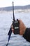 A man holds a portable walkie-talkie in his hand to communicate with other people in winter.