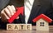 A man holds a red arrow up above the word Rate and a wooden house. The concept of raising interest rates on mortgages. The