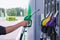 Man holds a refueling gun in his hand for refueling cars. Gas station with diesel and gasoline fuel close-up