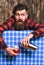 Man holds shaker on plaid tablecloth background.