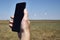 A man holds a smartphone in his hand against the background of a modern wind farm . Mobile phone communication. Modern