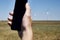 a man holds a smartphone in his hand against the background of a modern wind farm . Mobile phone communication. Modern