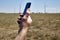 a man holds a smartphone in his hand against the background of a modern wind farm . Mobile phone communication. Modern