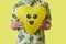 man holds a smiley yellow heart-shaped balloon