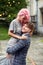 Man holds tender woman with pink hair standing against the wind