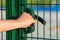 A man holds on to a door handle and opens an iron door to a sports ground. Entrance to industrial facilities