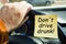 A man holds on to the steering wheel, next to a sticker with the inscription - Do not drive drunk