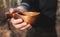 A man holds a traditional wooden Kuksu mug. Autumn forest, close-up