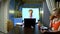 A man holds a video conference at home in the kitchen his wife eats at the table