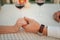 Man holds woman`s hand in cafe on background of wineglasses. Closeup.