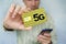 Man holds a yellow SIM card with the inscription 5G and a mobile phone in his hand. Replacing the SIM card and switching to high-