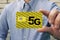 man holds a yellow SIM card with the inscription 5G for mobile phone in his hand. Replacing the SIM card and switching to high-