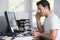 Man in home office on telephone using computer