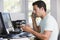 Man in home office on telephone using computer