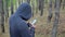 Man in a hood in the forest with a navigator in a smartphone