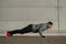 A man in a hoodie jumps while doing push-ups outdoors.