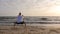 Man in horse stance practicing asian martial arts on seashore at sunset