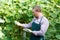 Man horticulturist in apron working with marrow seedlings in garden
