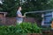 A man is hosing outdoor plants in the garden. Jet spraying of water in daylight. Gardening and hobby concept