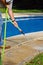 Man hosing pool paving, Spain.