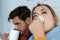 Man with hot drink and woman with napkin having runny nose