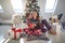 Man  hugging gorgeous mature young brunette in front of christmas tree beside pile of presents