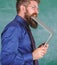 Man hungry for knowledge. Thirst of knowledge. Teacher bearded man bites modern laptop chalkboard background. Hipster