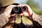 Man hunter with shotgun looking through binoculars in forest