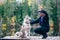 Man with a husky dog â€‹â€‹on the pier of a beautiful lake, autumn mood. Young man training a dog in nature