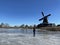 Man ice skating on a frozen lake with the windmill from IJlst