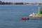 A man in an inflatable motorboat, swims past a stone breakwater with a dangerous signal beacon. Rest on the water in paradise.