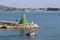 A man in an inflatable motorboat, swims past a stone breakwater with a dangerous signal beacon. Rest on the water in paradise.