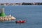 A man in an inflatable motorboat, swims past a stone breakwater with a dangerous signal beacon. Rest on the water in paradise.