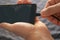 Man inserts a cable into a mobile phone for charging, hands closeup view.