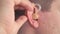 Man inserts a hearing aid into her ear close up
