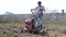 A man inspects the cultivator, cleans it of grass and starts the motor to start work in the field