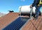 Man installing alternative energy photovoltaic solar panels on roof