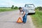 Man installing emergency sign on road near his car