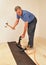 Man installing hardwood floor using nailer