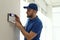 Man installing home security system on white wall in room