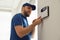 Man installing home security system on white wall in room