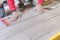 Man installing rectangular shaped floor tiles in kitchen. Applying adhesive before installation and verifying afterwards