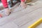 Man installing rectangular shaped floor tiles in kitchen. Applying adhesive before installation and verifying afterwards